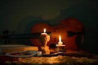 A warm candlelit scene featuring a violin, books, and candles in an artistic arrangement.