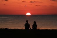 Silhouette of a couple holding hands at sunset, gazing at the sea horizon in Turkey.