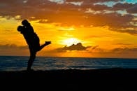 Silhouette of a romantic couple embracing on a beach at sunset, showcasing love and tranquility.